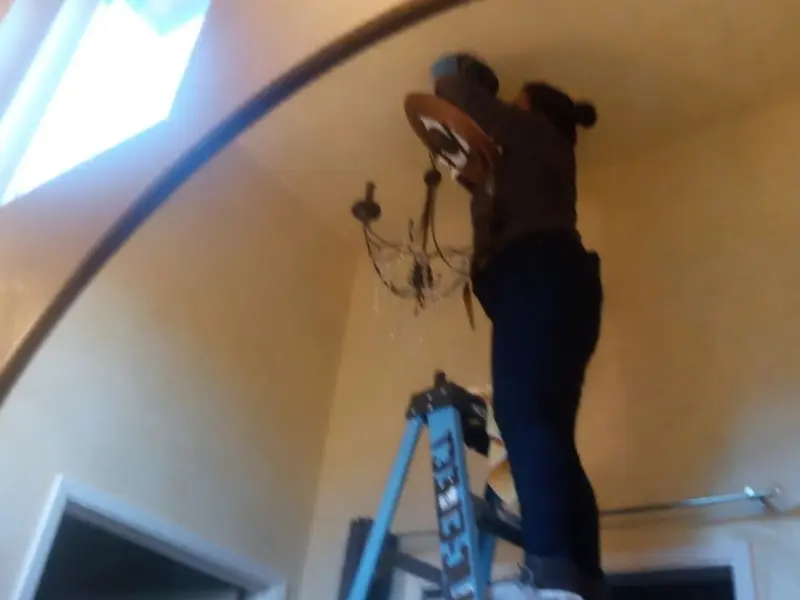Electrician installing a chandelier in a Damascus residence
